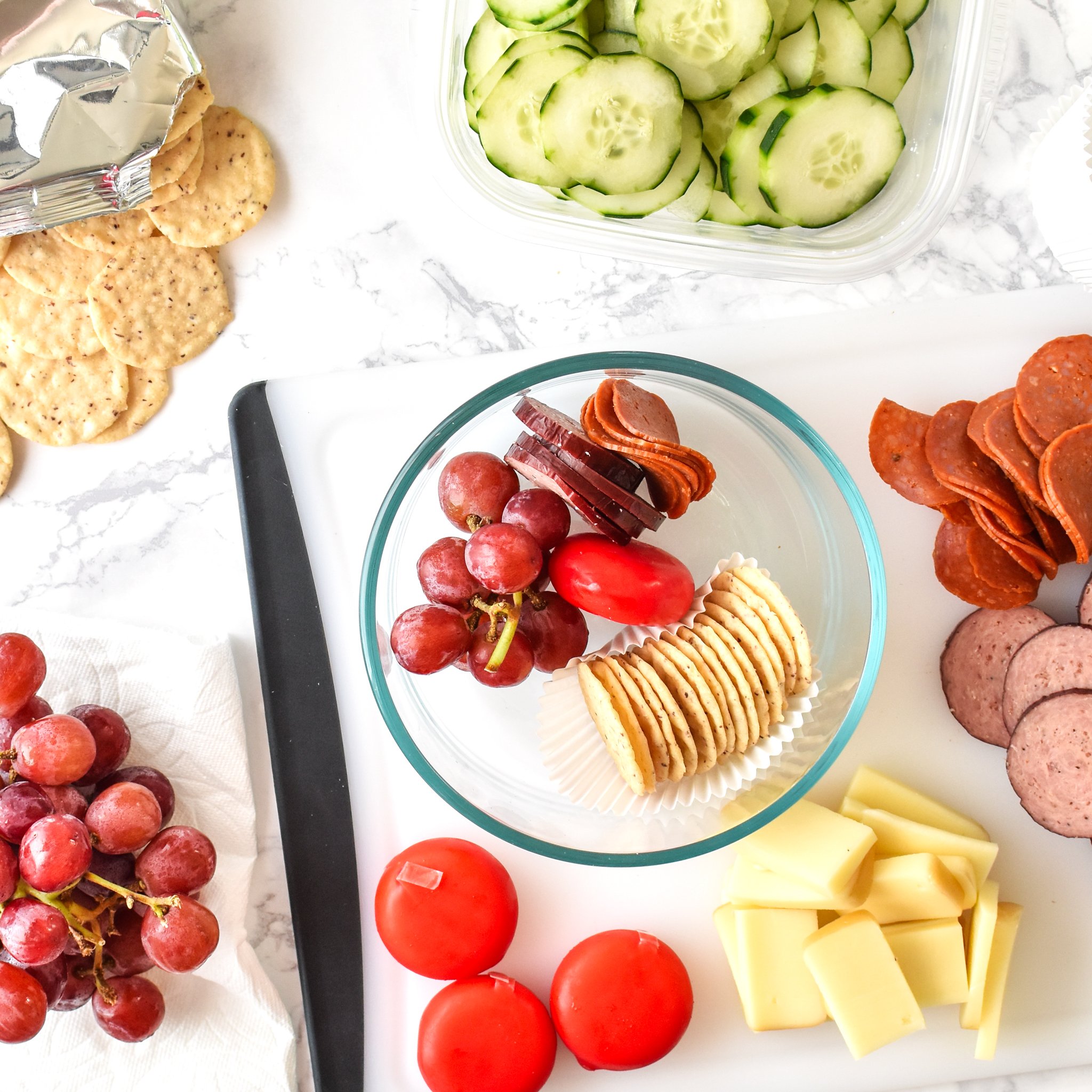 Assembling adult lunchables with crackers cheese and meat.