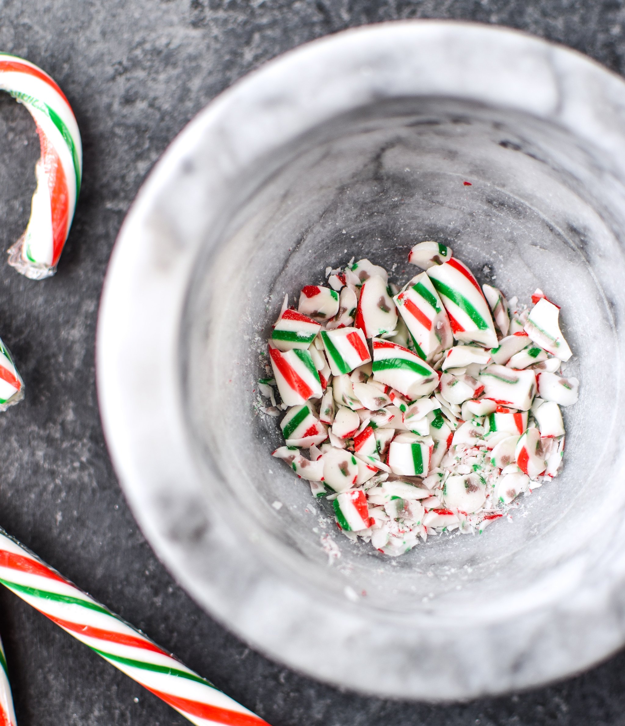 Crushed peppermint candy canes in a mortar and pestle viewed from above.