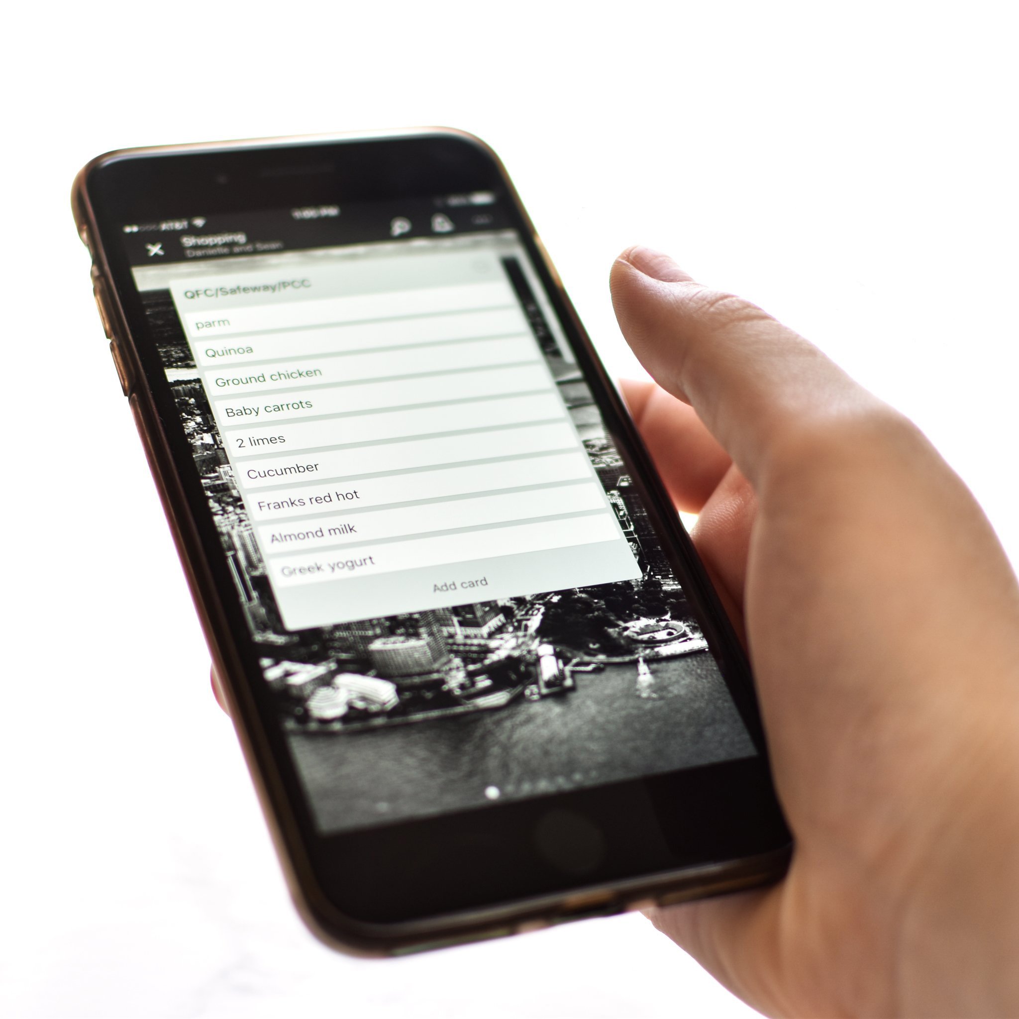 Holding a phone with a shopping list displayed using the app Trello.