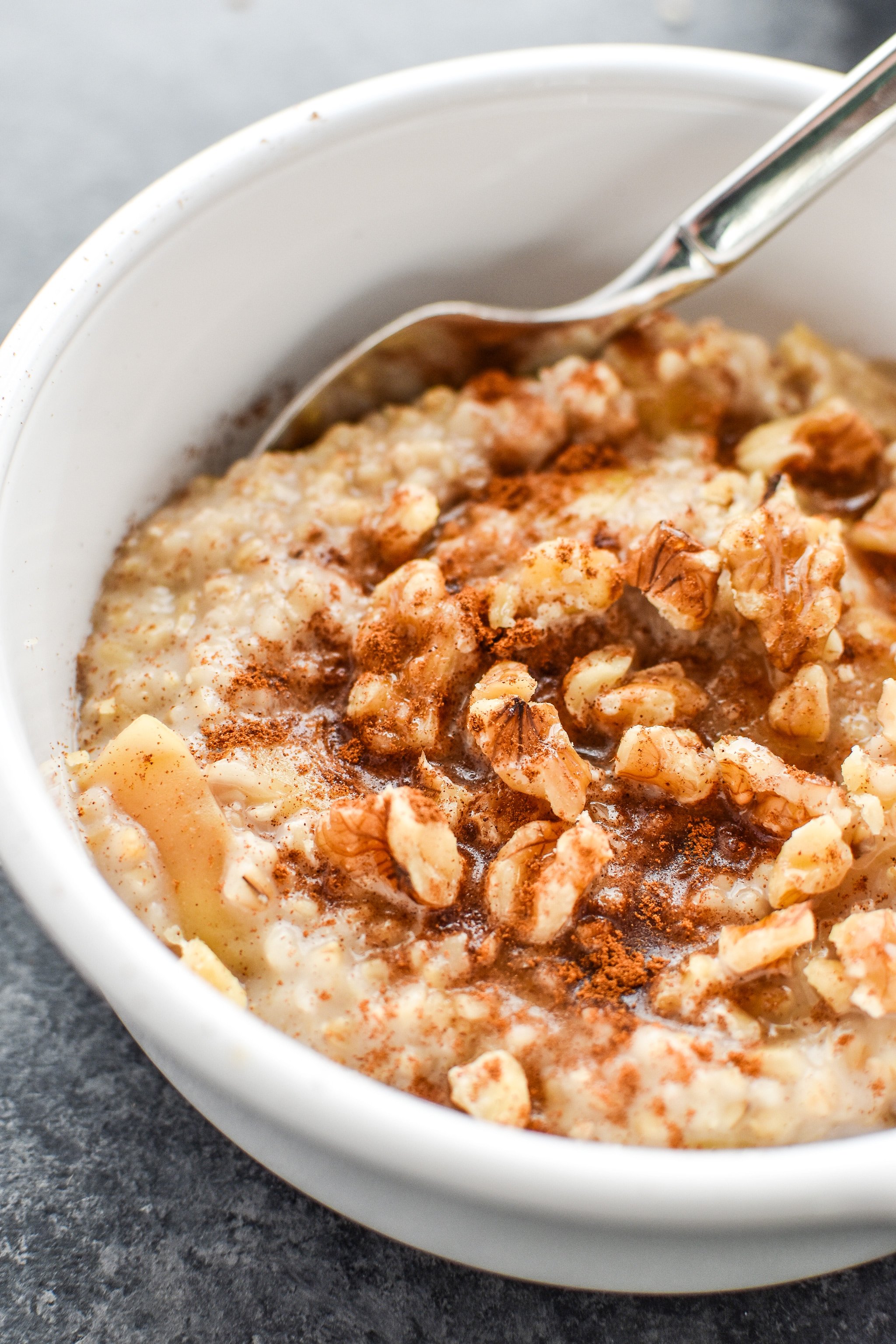 A bowl of cooked steel cut oats with nuts and cinnamon.
