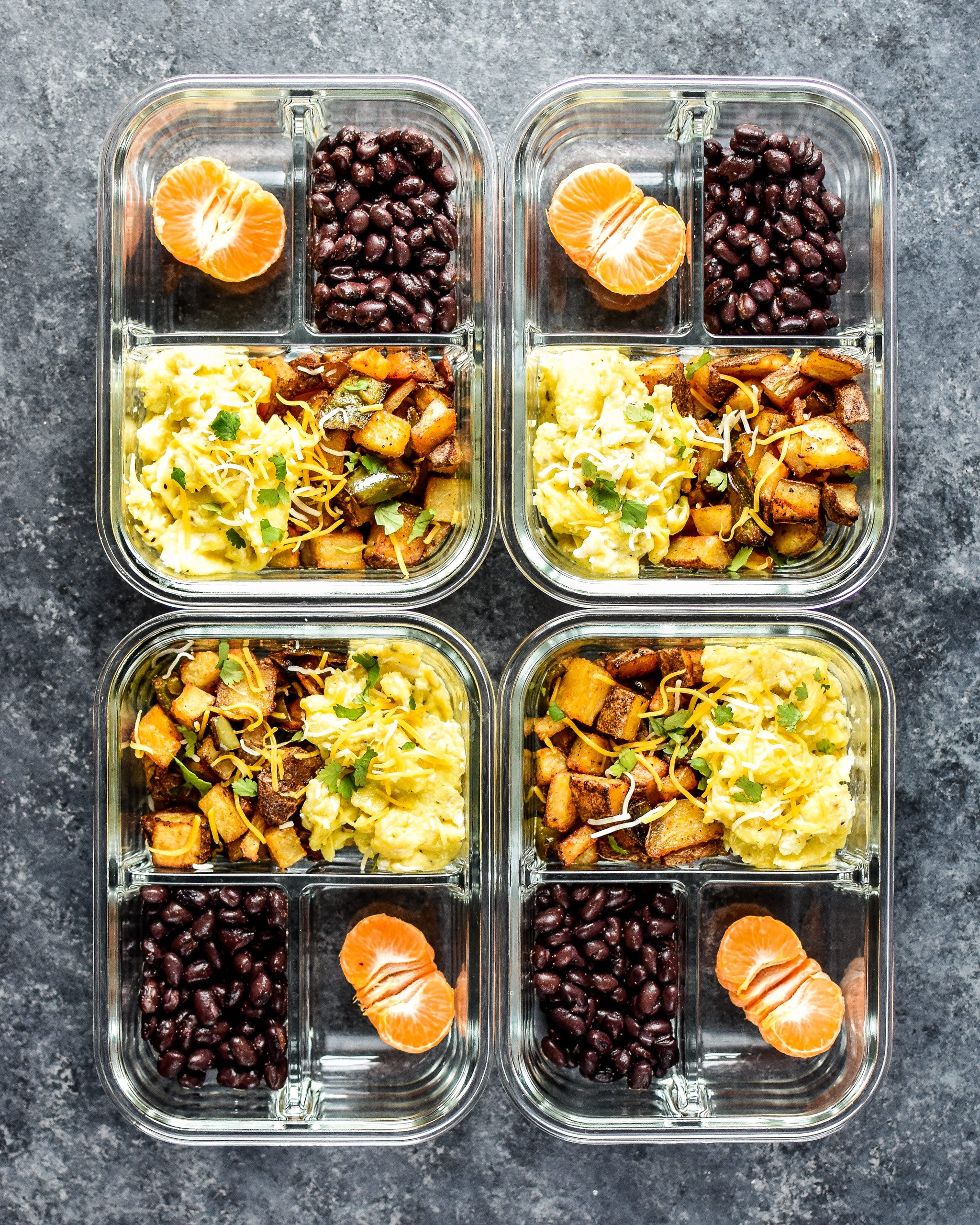 Four meal prepped servings of breakfasts with potatoes, eggs, peppers and beans.