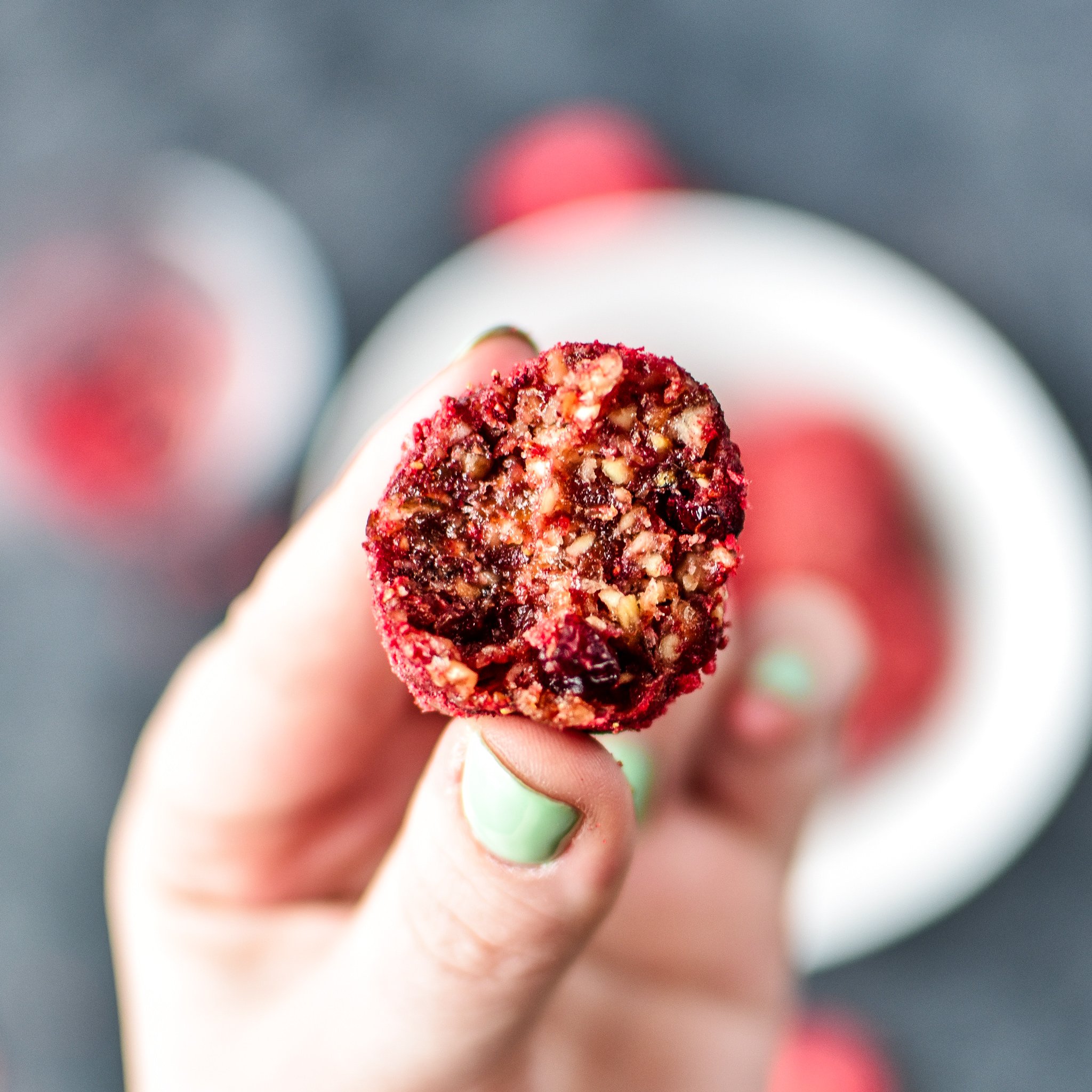 A hand holding a spiced berry bliss ball.