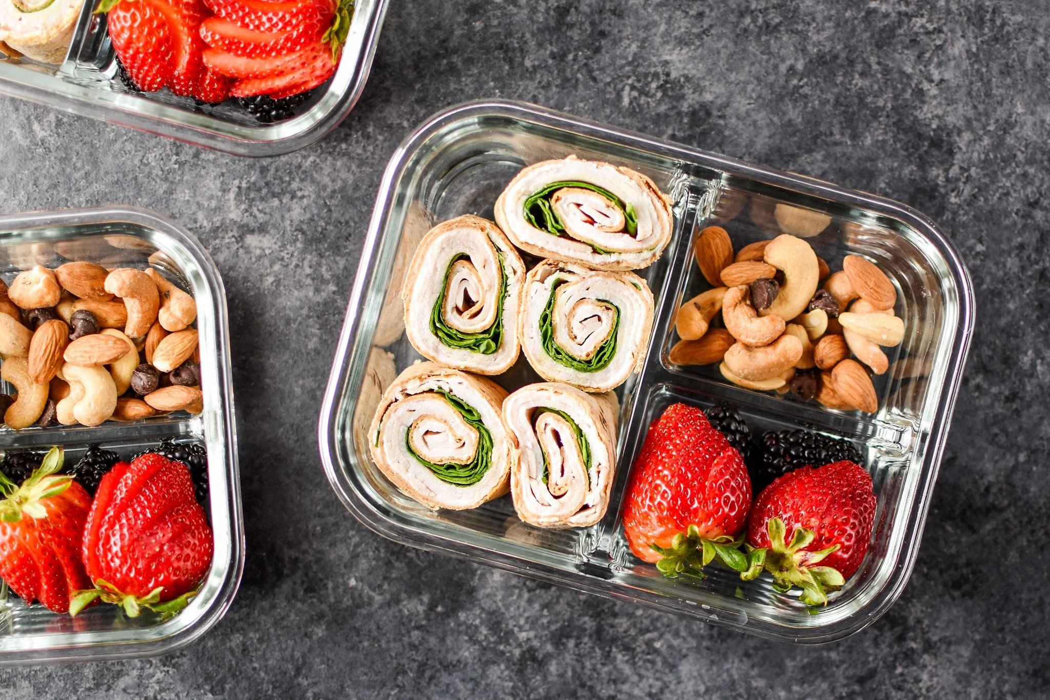 Ein Blick auf die Easy Turkey Pinwheel Meal Prep von oben mit Beeren und Nüssen.