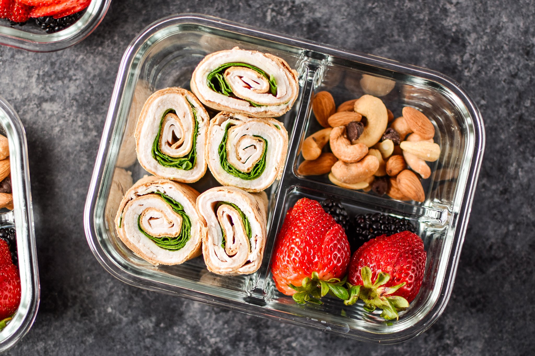 A turkey pinwheel meal prep with berries and nuts.