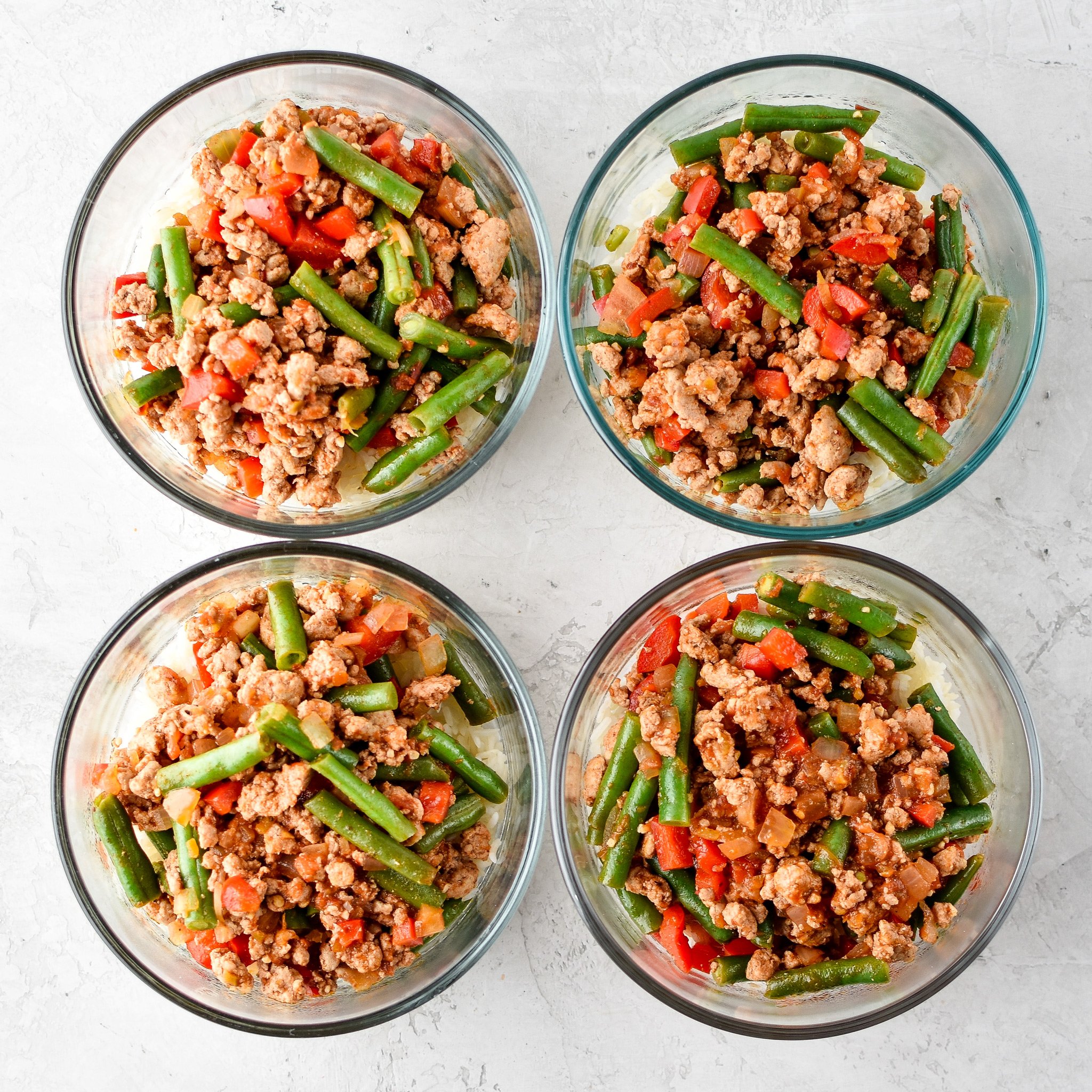 A set of four lunches meal prepped into glass Pyrex containers.