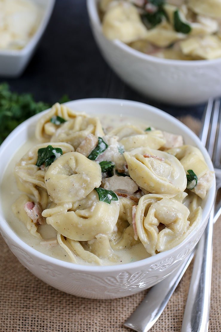 Instant Pot tortellini alfredo with chicken, spinach and bacon in a bowl ready for dinner.