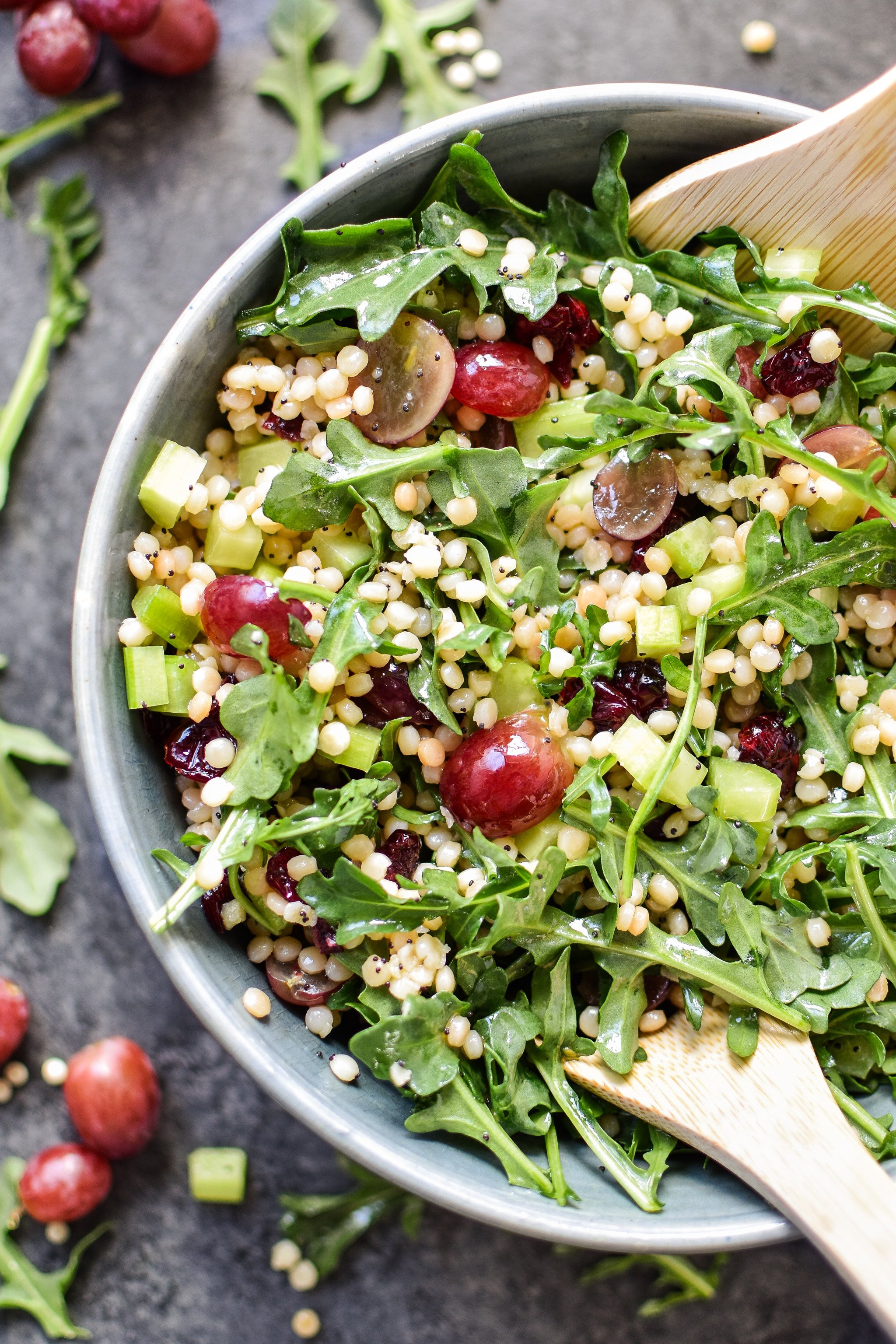 Make-Ahead Lemon Poppyseed Couscous Arugula Salad viewed from above in a serving bowl with utensils.