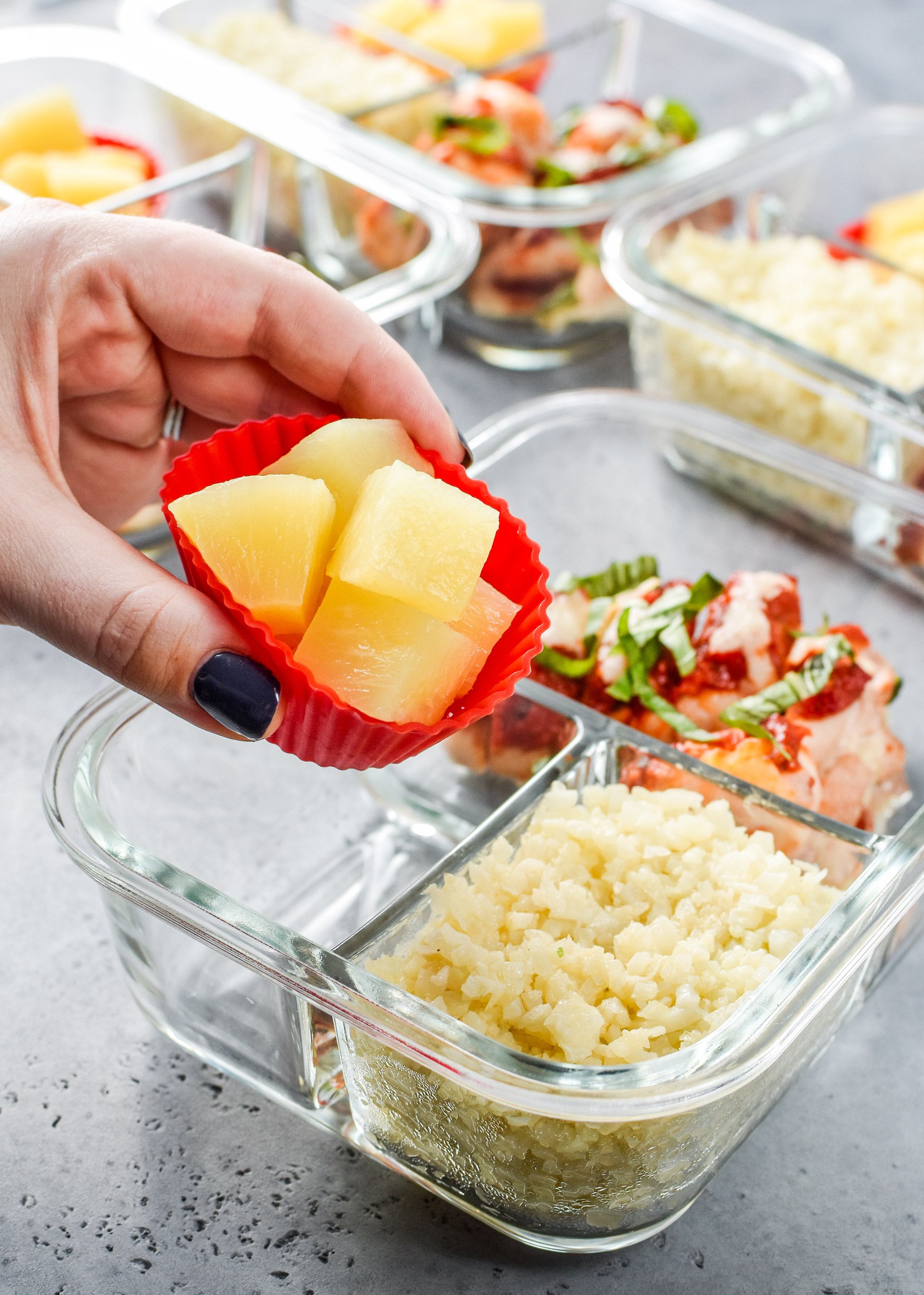 Pizza chicken roll ups meal prep with pineapple inside silicone baking containers for easy removal.