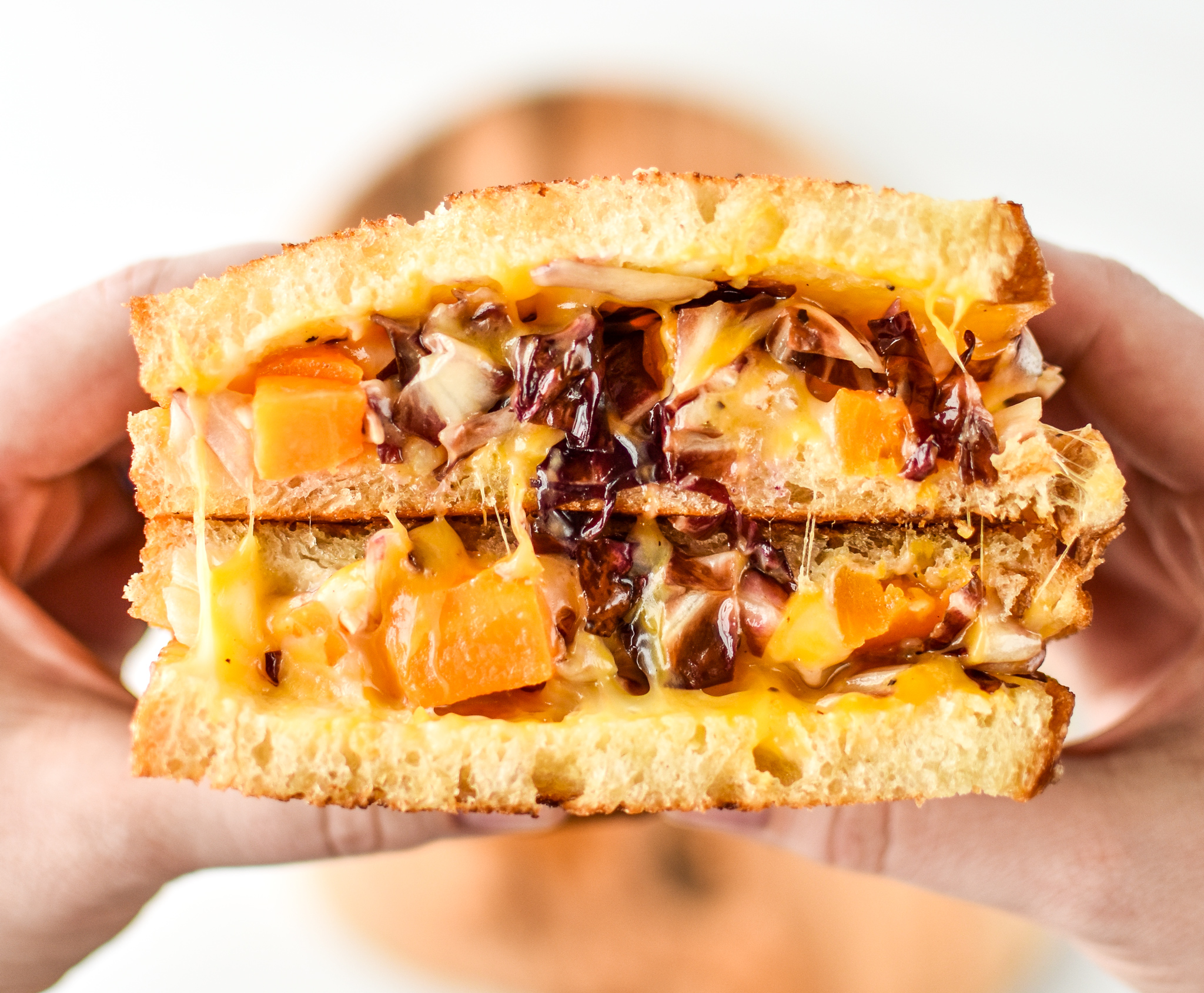 Holding a roasted squash salad grilled cheese sandwich
