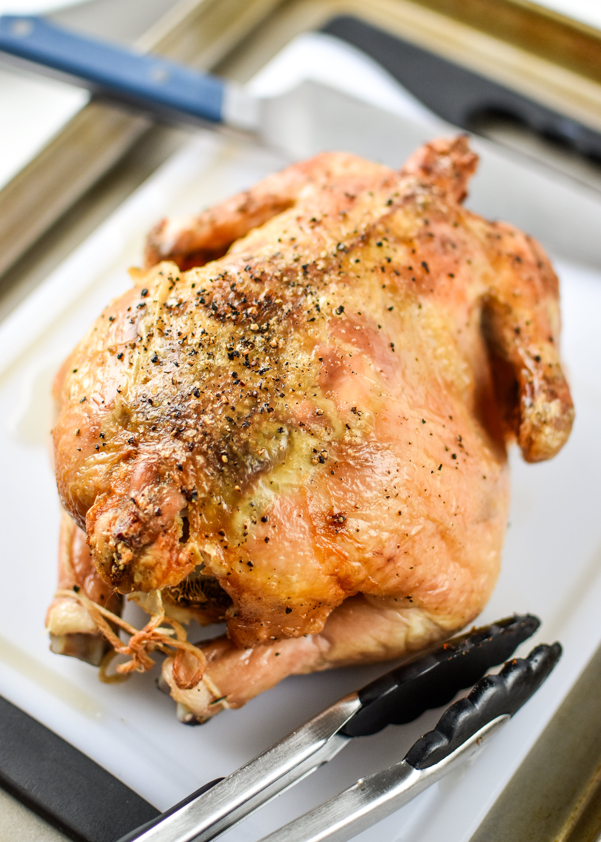 Simple whole roast chicken resting on a cutting board.