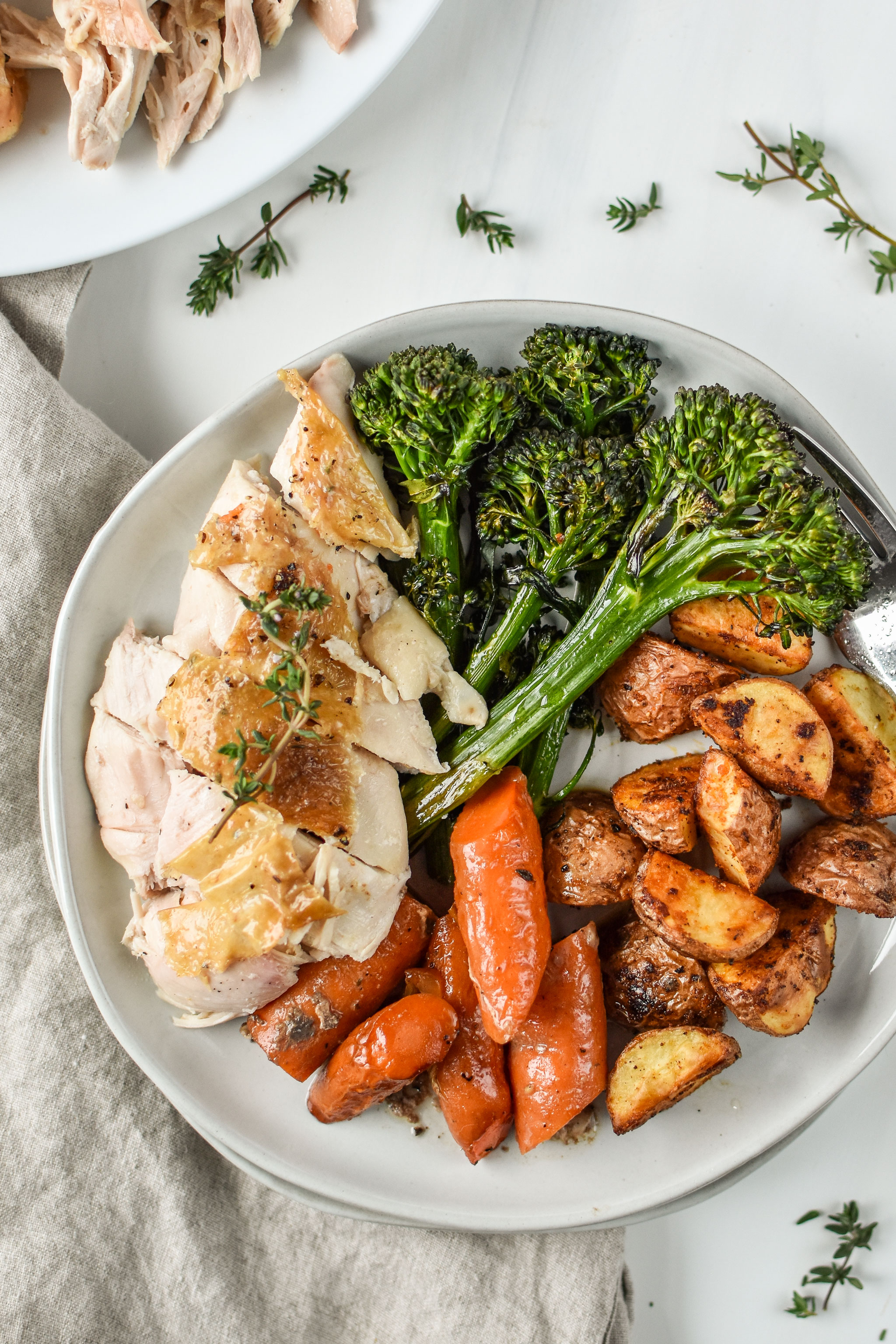 Simple whole roast chicken plated with broccolini, potatoes and carrots, a perfect Whole30 dinner!