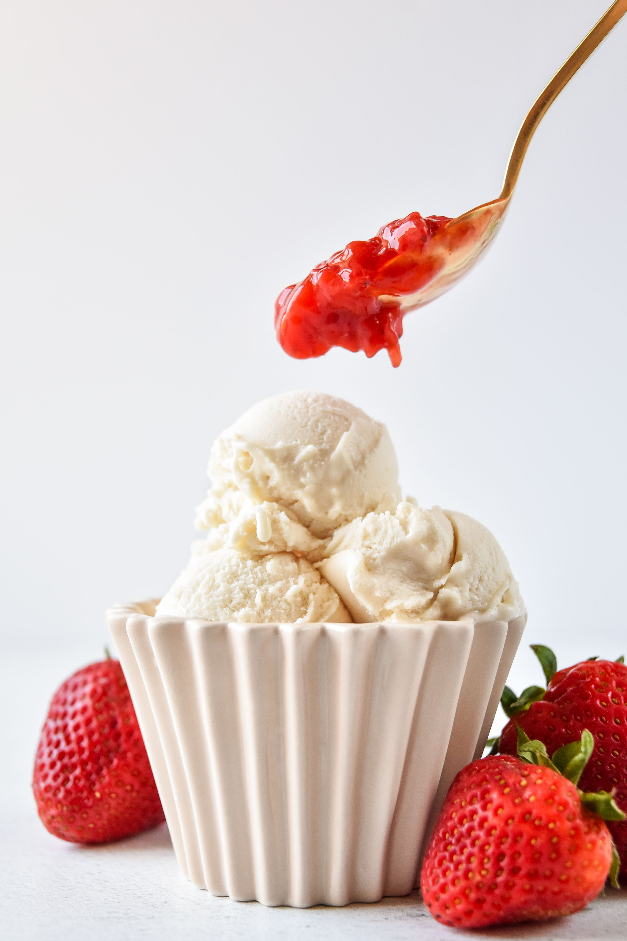 adding easy strawberry sauce on some vanilla ice cream