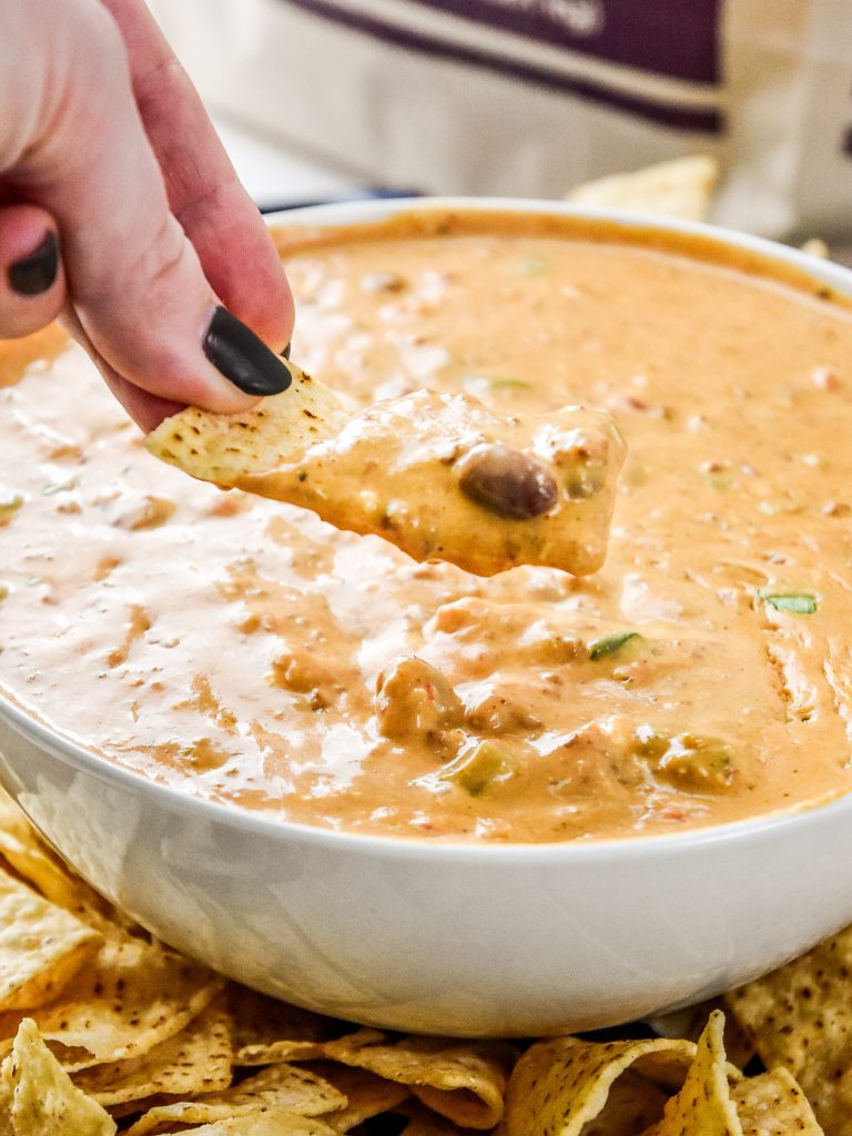 dipping a chip into the chili cheese dip.