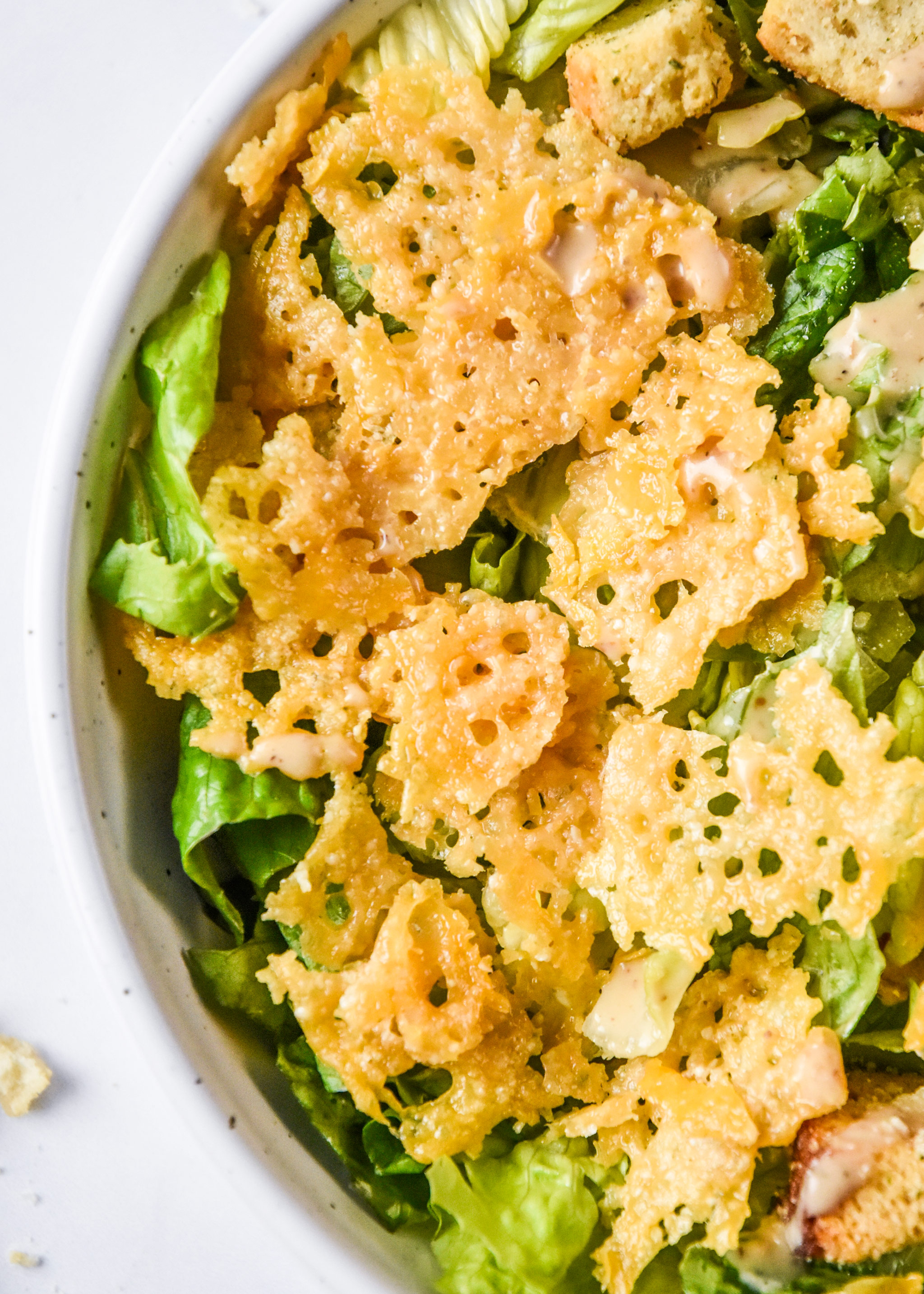 baked parmesan crisps all crunched up on a caesar salad