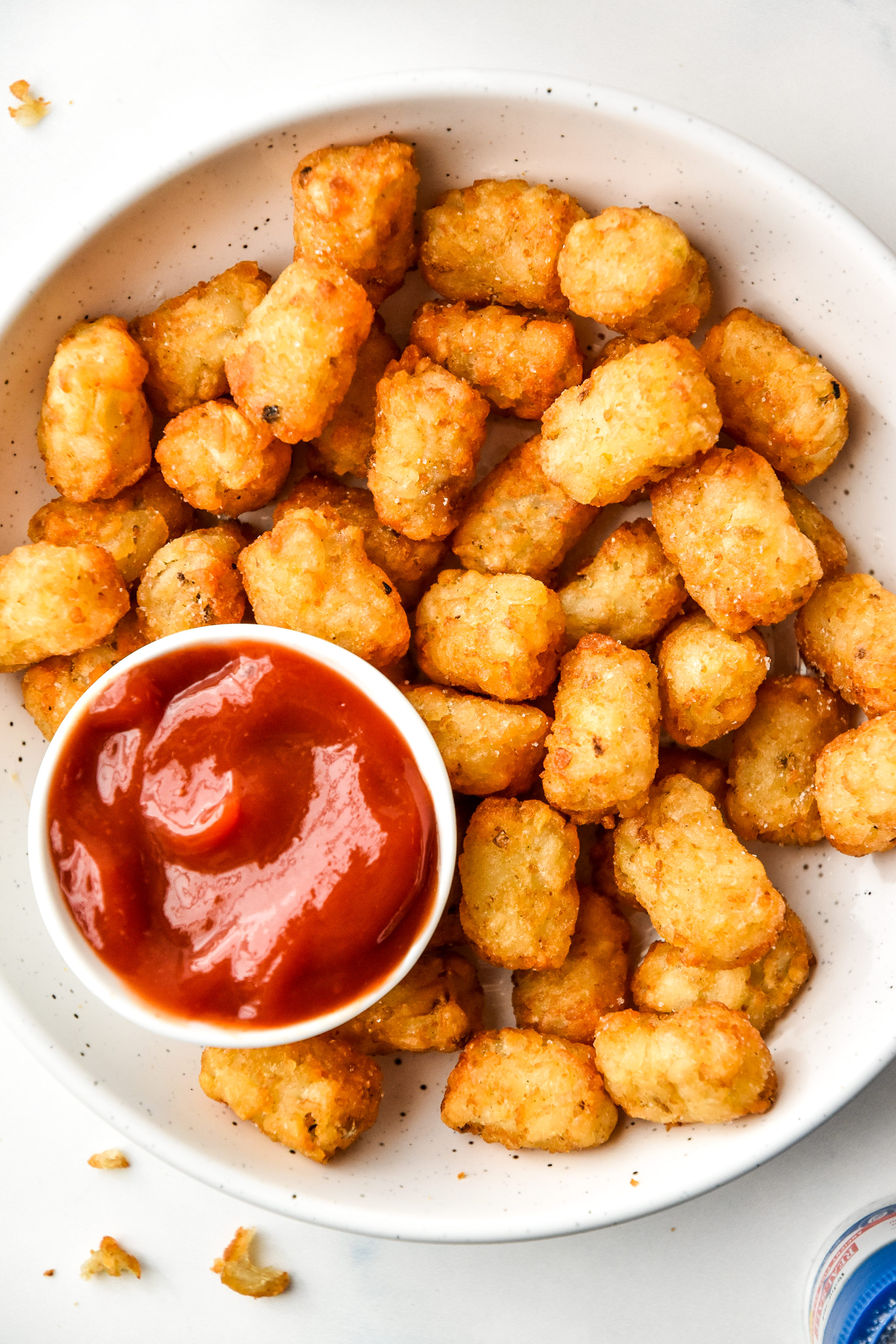 how to cook frozen tater tots in an air fryer in a white bowl served with ketchup