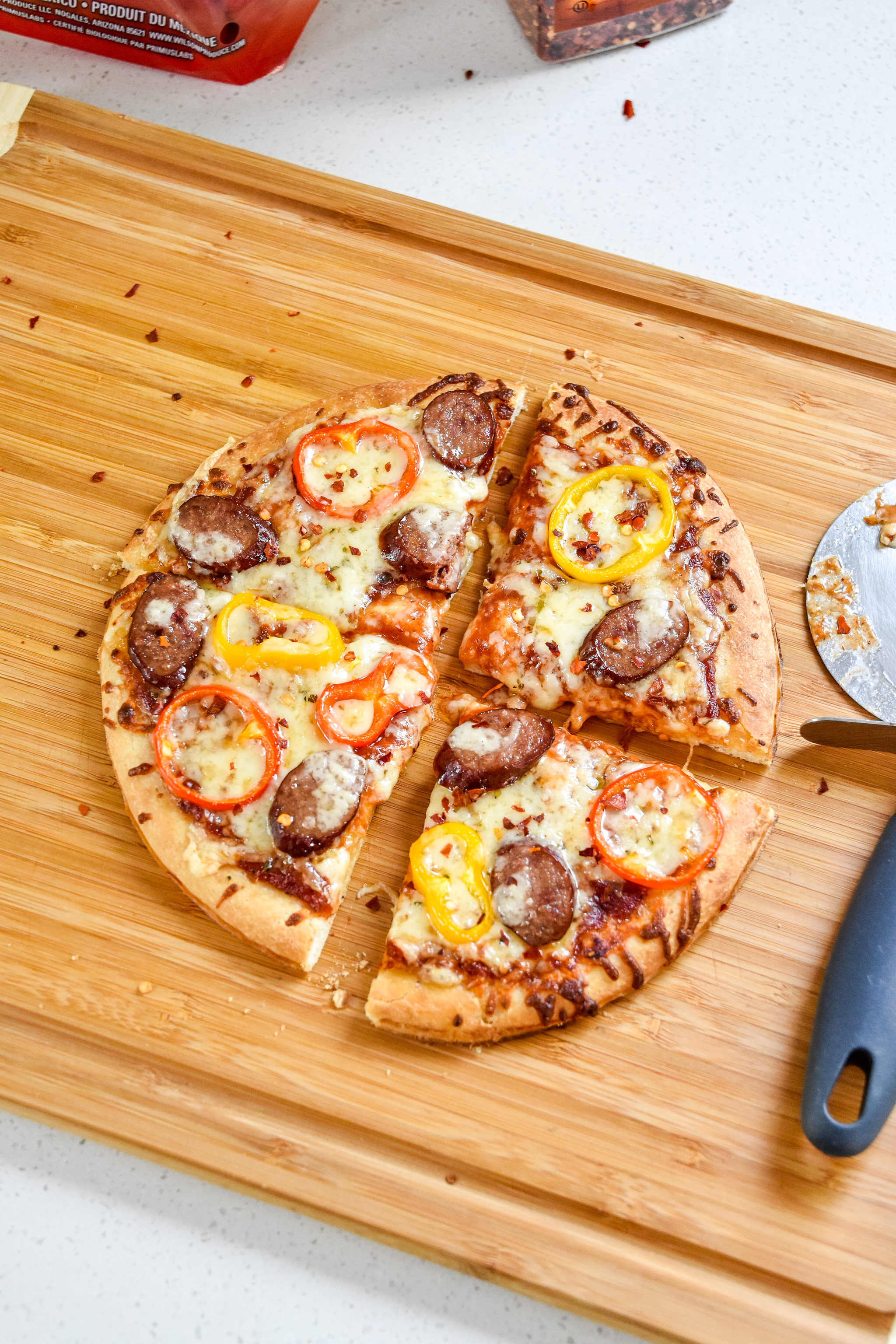 sausage and pepper personal pizza fresh from the oven cut with a pizza cutter