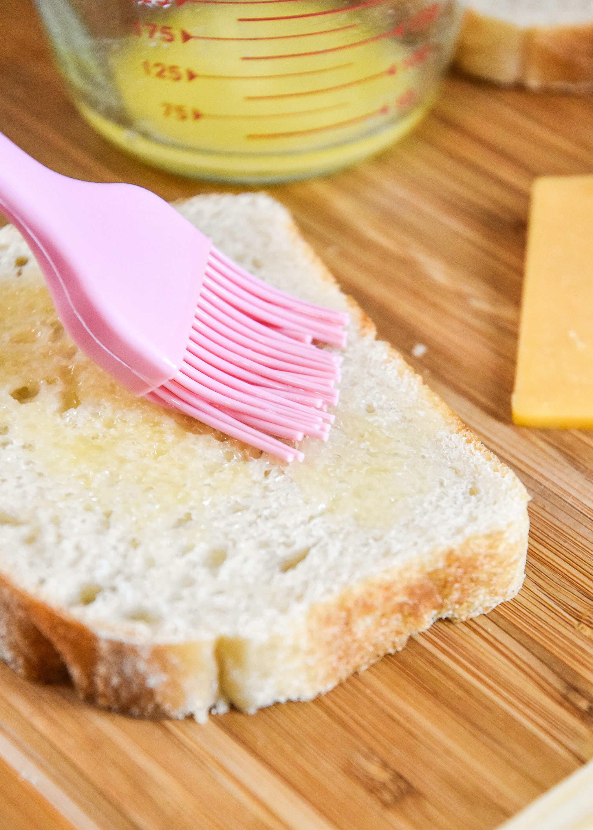 brushing butter on bread to make a grilled cheese sandwich