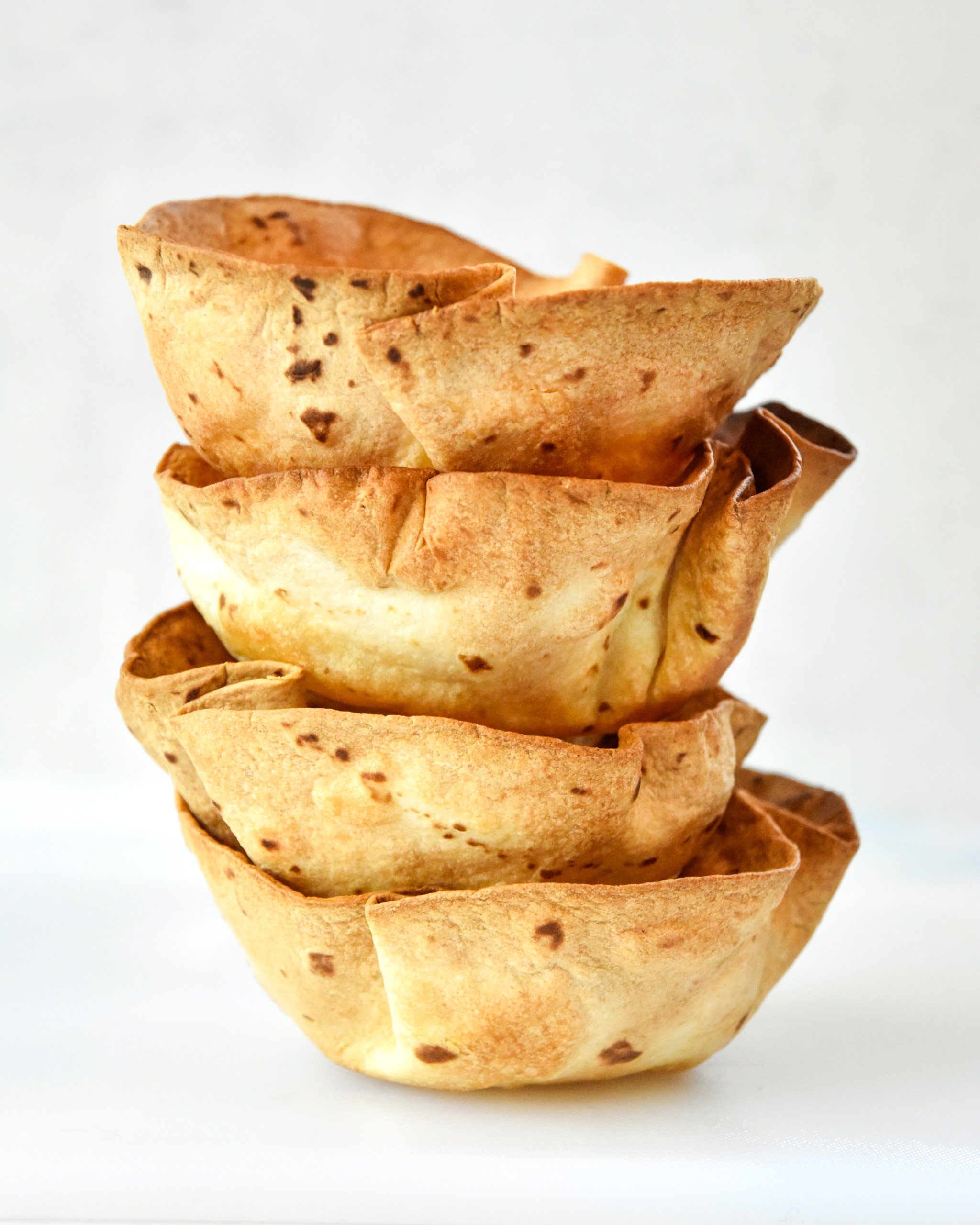 4 flour tortilla bowls stacked with a white background