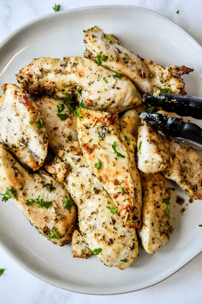 a plate of air fryer chicken tenders with tongs on the side.