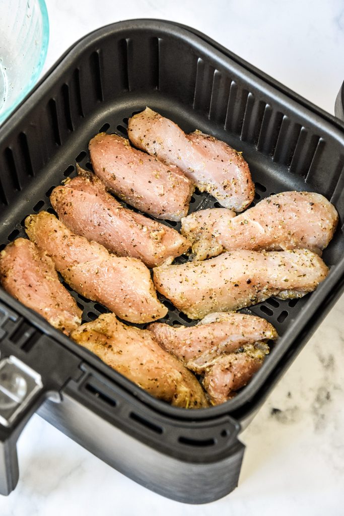 raw marinated chicken in the air fryer basket about to be cooked.