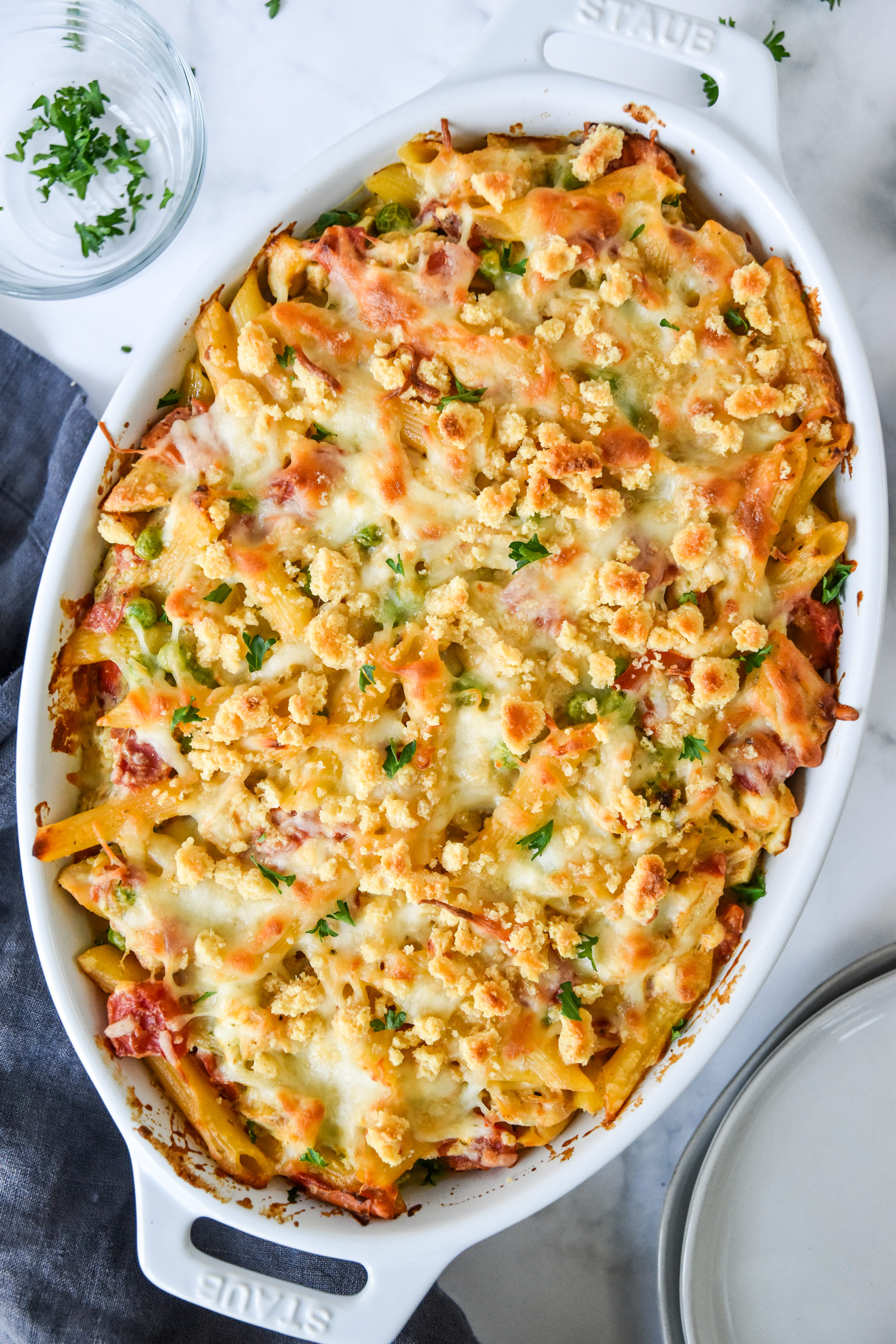 creamy pesto pasta chicken bake fresh from the oven in a white baking dish.