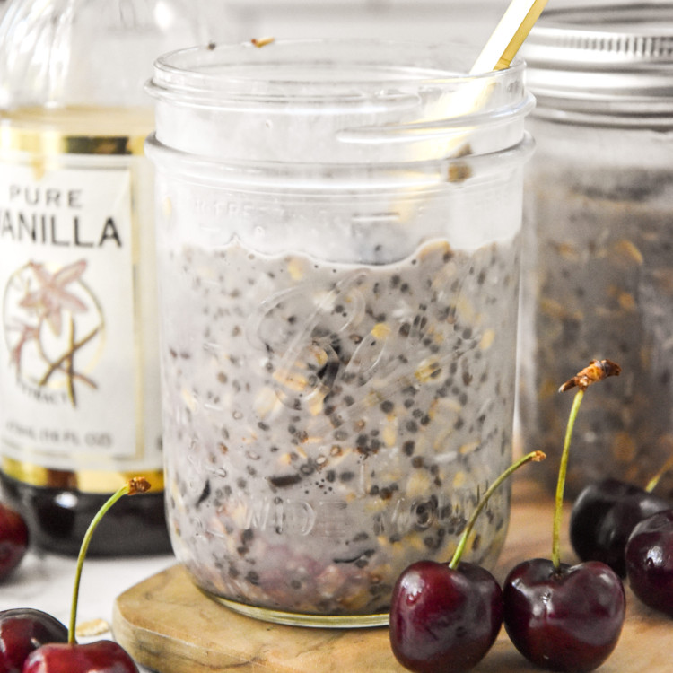 cherry vanilla overnight oats in a mason jar with a gold spoon.