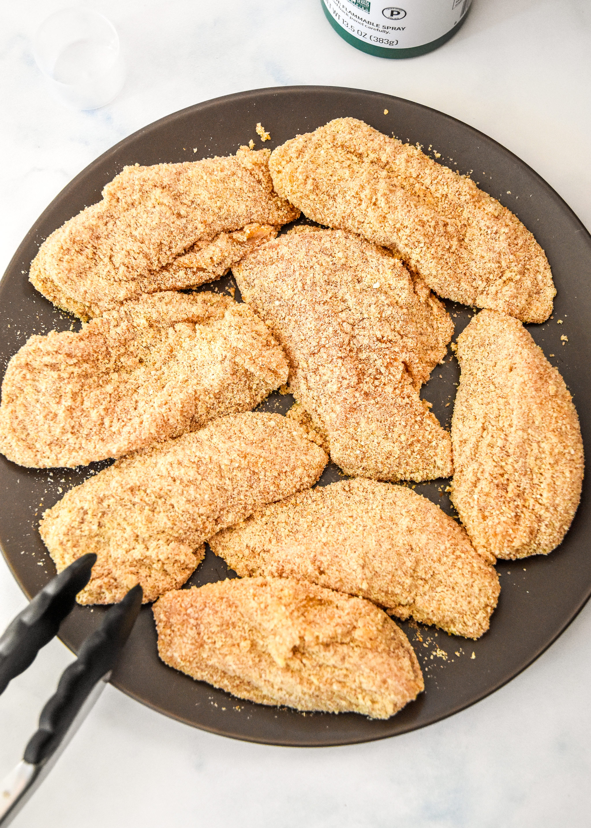 breaded chicken tenders on a plate before cooking.