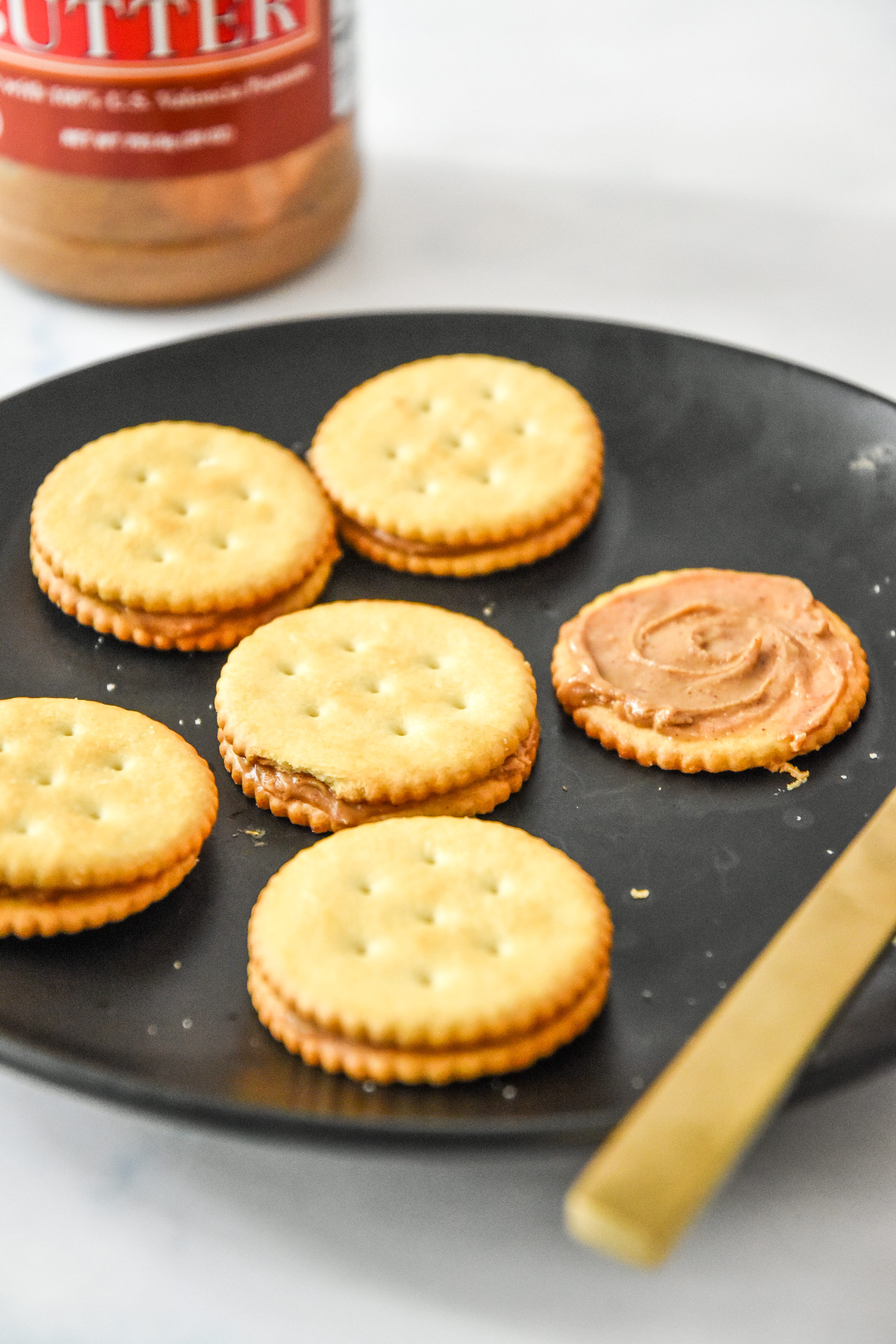 spreading peanut butter on crackers with a butter knife.