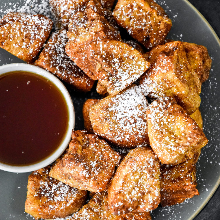 air fryer french toast bites on a plate with a cup of maple syrup.