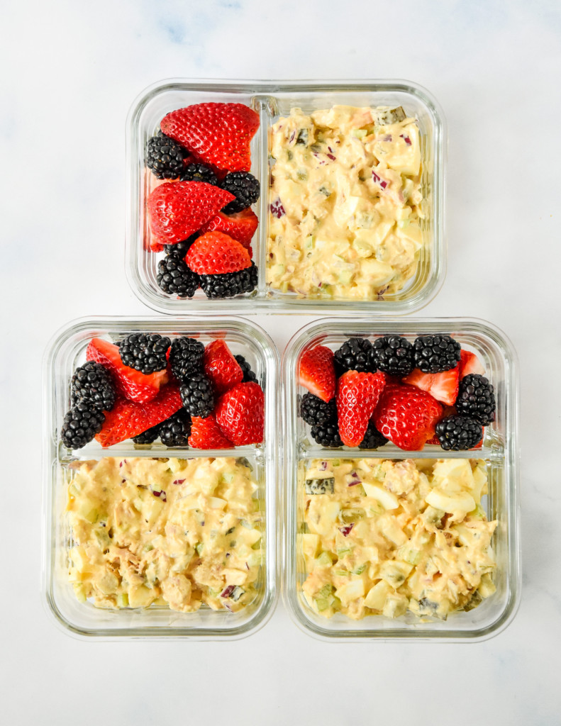 tuna egg salad and berries in glass meal prep containers.