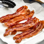 perfect oven cooked bacon on a paper towel lined plate.