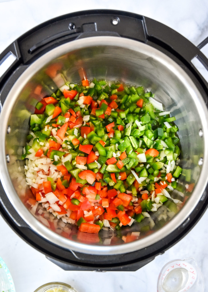 diced peppers and onions cooking in oil in the instant pot liner.