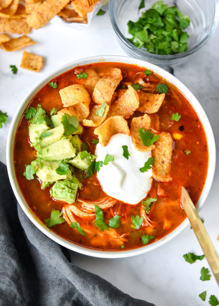 instant pot no bean chicken chili in a bowl with avocado, corn chips and cilantro on top.