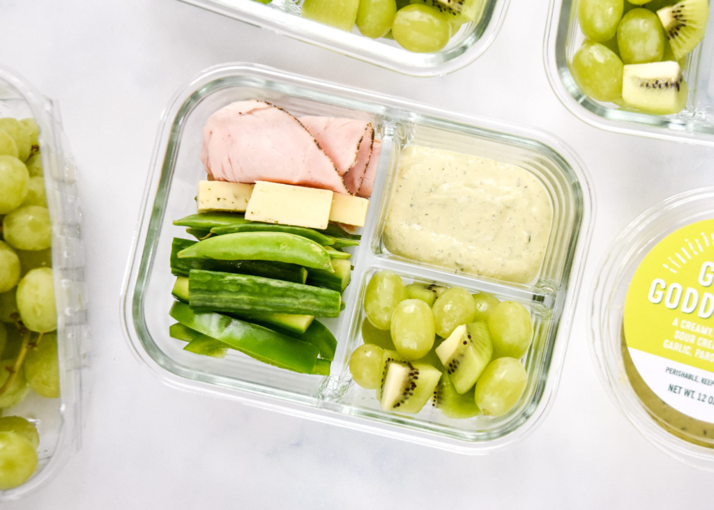close up of green food lunch box meal prep with peppered turkey, havarti cheese, green fruits and veggies.