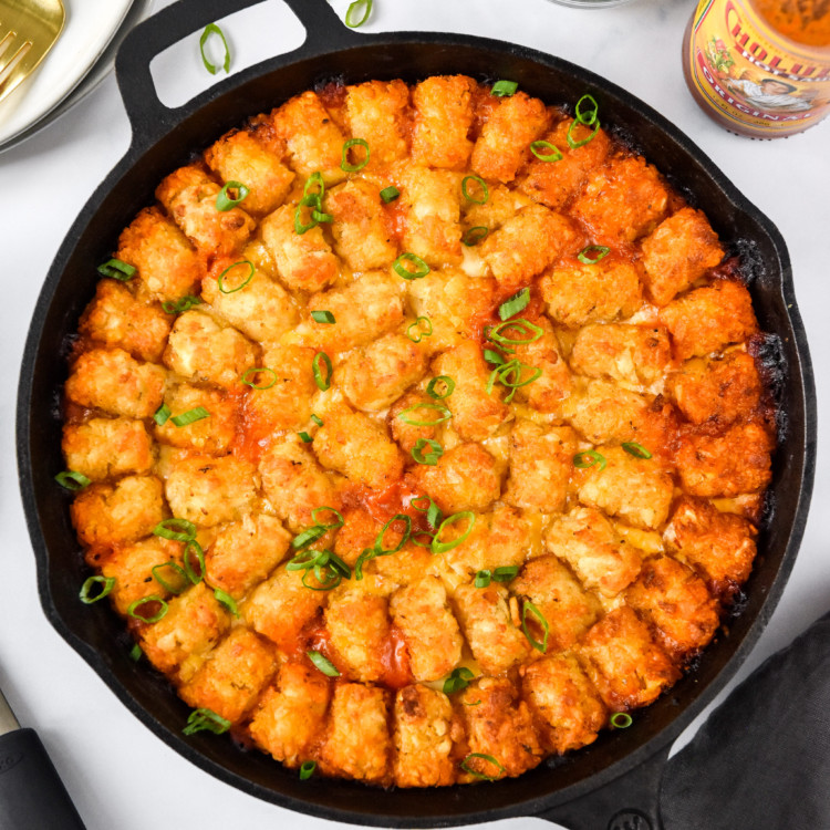 turkey sloppy joe tater tot casserole cooked in a cast iron on a table.