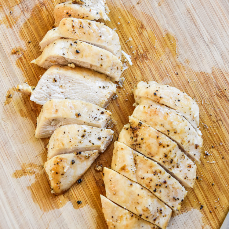 sliced chicken on a cutting board is one way how to cook chicken for meal prep.