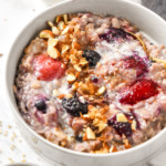 bowl of stovetop triple berry egg white oatmeal in a bowl with almonds on top.