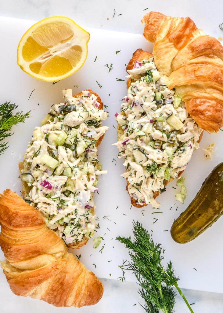 two croissants with dill pickle chicken salad on top.