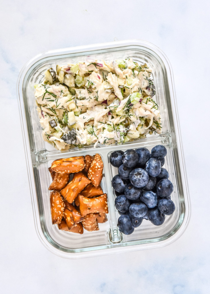 dill pickle chicken salad in a meal prep container with blueberries and pretzels.
