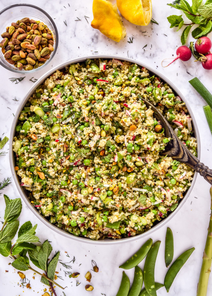 spring vegetable quinoa salad in a serving bowl with wooden spoon.