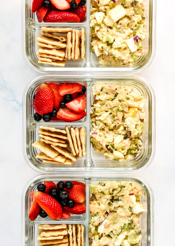 tuna egg salad meal prep with crackers and berries in glass meal prep containers.