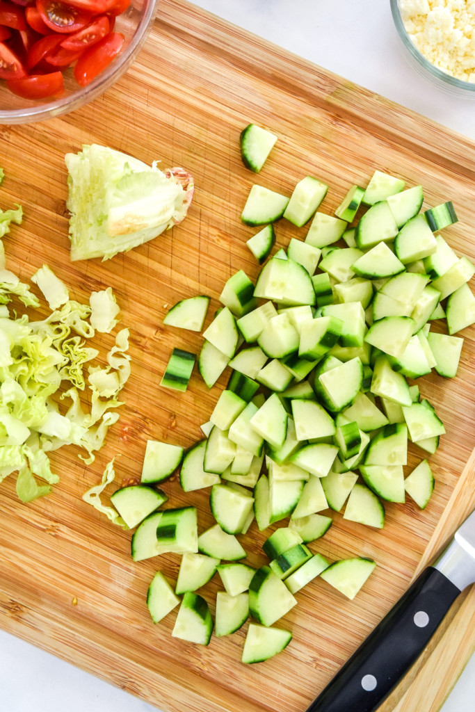 peeling and chopping the cucumber for the greek chicken salad meal prep bowls.