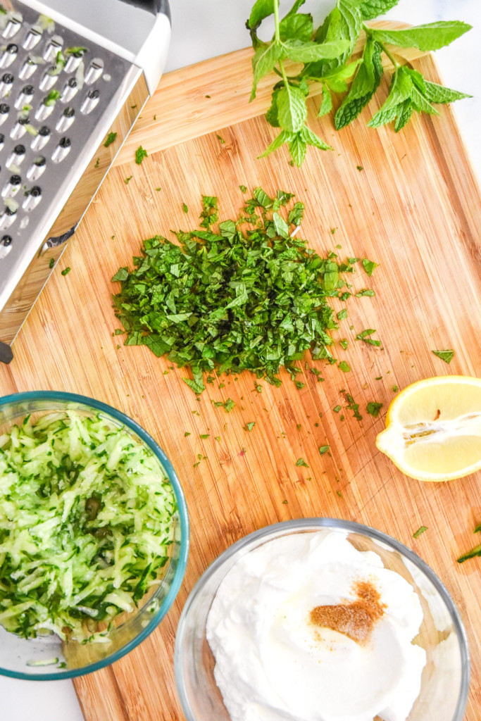 chopped mint and ingredients on a cutting board to make the cucumber raita.