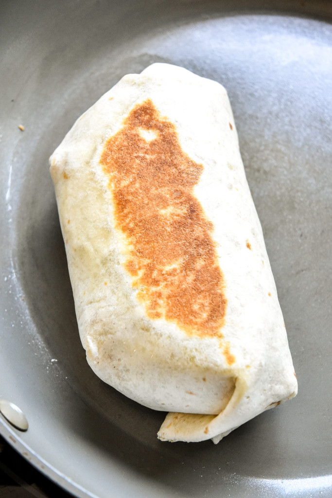 heating a meal prep soy chorizo breakfast burrito on the stovetop.
