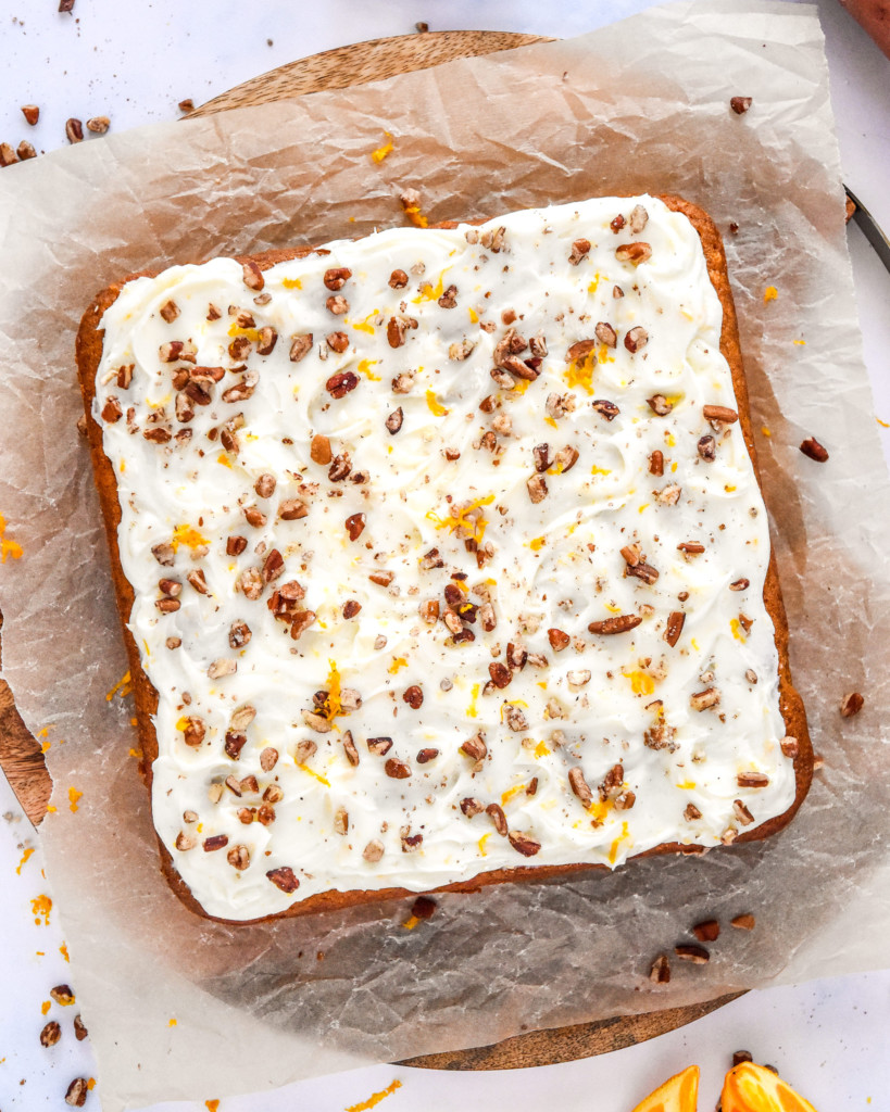 sweet potato spice cake with cream cheese frosting and chopped pecans on top.