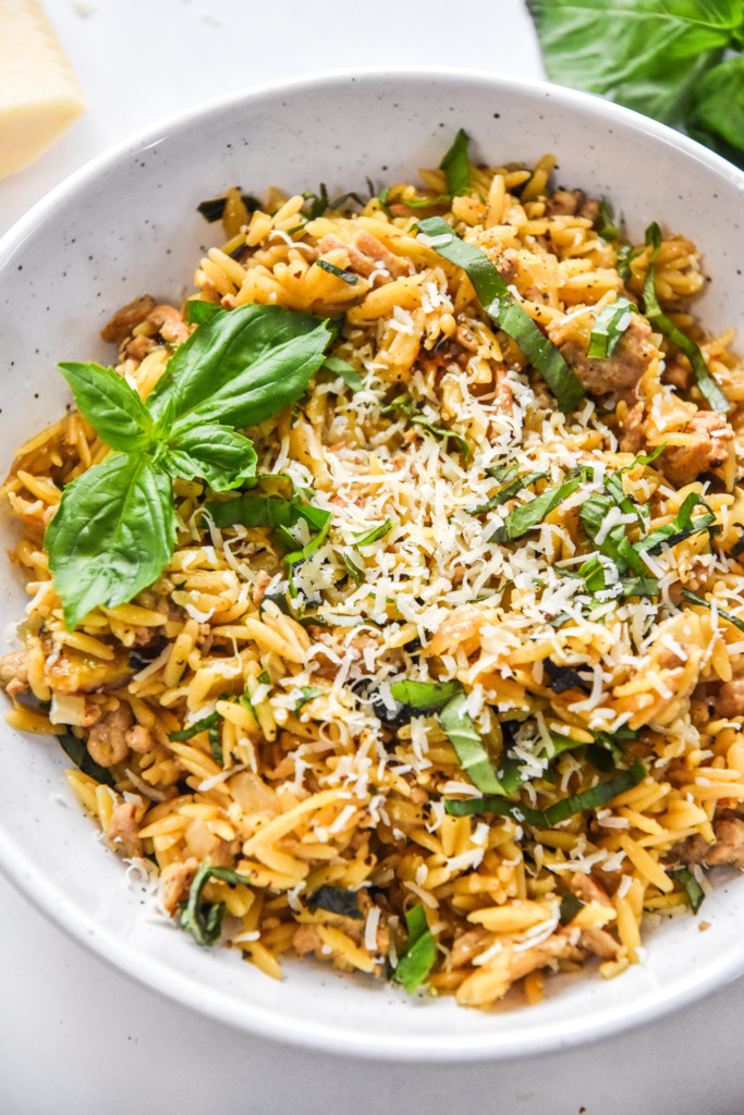 a bowl of ground turkey zucchini orzotto with fresh grated parmesan cheese on top.