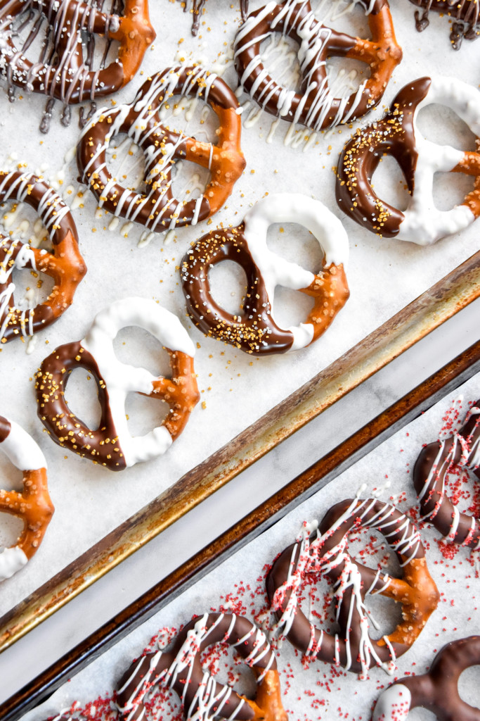 homemade chocolate dipped pretzels on a sheet pan lined with parchment paper.