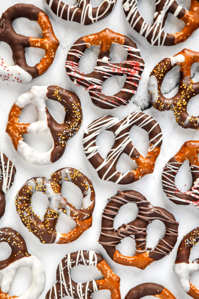 homemade chocolate dipped pretzels laying flat on a white background.