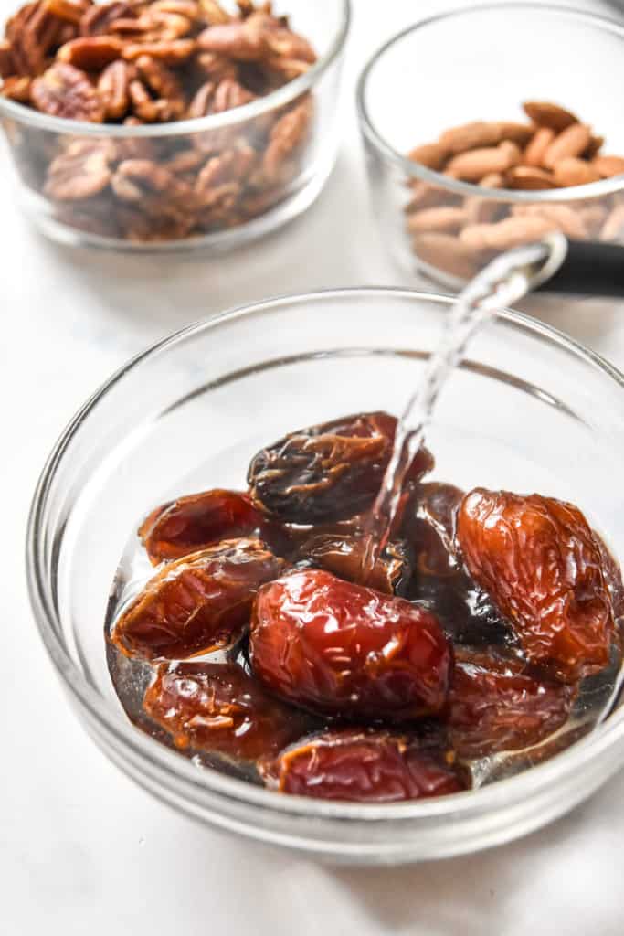 pouring hot water into a bowl of medjool dates.