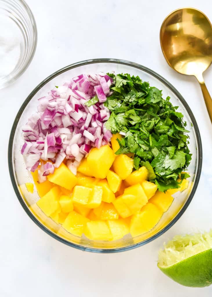 mango salsa ingredients in a glass bowl before stirring.